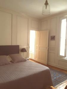 a bedroom with a bed and two windows and a door at La Maison des Thermes, Chambre d'hôte in Saintes