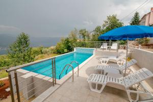 a swimming pool with lounge chairs and an umbrella at Apartments Mitrovic in Lustica