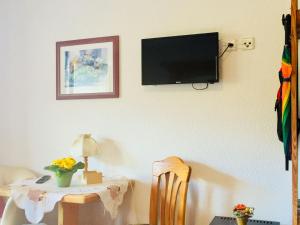 Habitación con mesa y TV en la pared. en Pension Hildegund, en Lauterbach