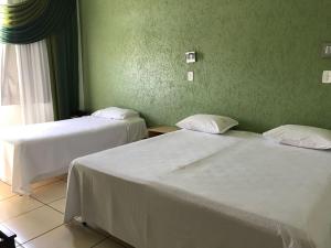 2 camas en una habitación con paredes verdes en Hotel Meri, en Conselheiro Lafaiete