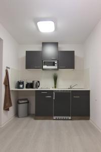 a kitchen with black cabinets and a microwave at Stax Motel in Gamstädt