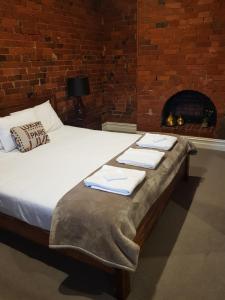 a bed with towels on it in a room with a fireplace at Sublime Spa Apartments in Wangaratta