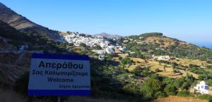 una señal frente a un pueblo en una colina en Limnes Home, en Moutsoúna