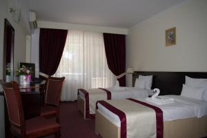 a hotel room with two beds and a desk at Hotel Europolis in Tulcea