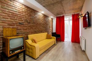 a living room with a yellow couch and a brick wall at Ma Xata in Tbilisi City