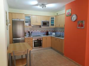 a kitchen with wooden cabinets and a table with a clock at Arinaga Beach & Pool Apartment in Arinaga