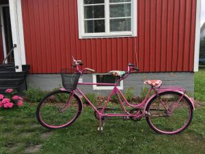 uma bicicleta rosa estacionada em frente a uma casa vermelha em Lingonberry Cottage em Ekenäs