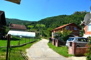 a dirt road in a village with a house and a car at Vacation Home "Cehic" in Kulen Vakuf