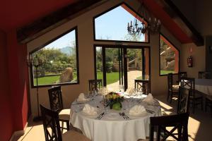 a dining room with a white table with chairs and windows at Hotel Zerbinetta in Dílar