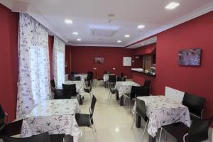 comedor con mesas, sillas y paredes rojas en Hotel HC Sigüenza, en Sigüenza