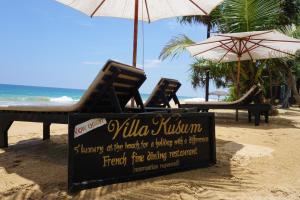a sign on the beach with chairs and umbrellas at Villa Kusum in Hikkaduwa