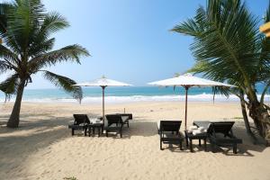 a group of tables and umbrellas on a beach at Villa Kusum in Hikkaduwa