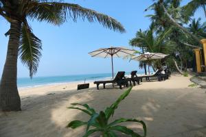 a beach with benches and umbrellas and the ocean at Villa Kusum in Hikkaduwa