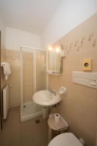 a bathroom with a toilet, sink, mirror and bathtub at Hotel Derby in Finale Ligure