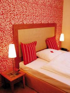 a bedroom with a bed with red pillows and a table at Wellings Romantik Hotel zur Linde in Moers