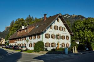 ein großes weißes Gebäude mit braunem Dach in der Unterkunft Gästehaus Enzianhof Hotel Garni in Oberammergau
