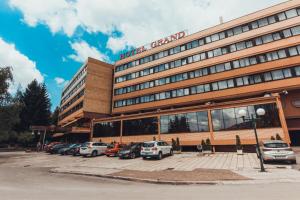 a hotel stand with cars parked in a parking lot at Hotel Grand in Sarajevo