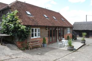 uma pequena casa com um banco e uma mesa em High Street Farm Barn em Newbury