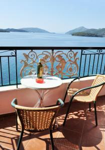 a table and chairs on a balcony with a bottle of wine at Logan's Beach Hotel in Nydri