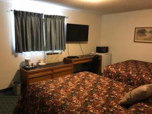 a hotel room with two beds and a desk at The Home Hotel in Boissevain