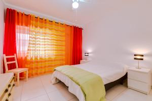 クアルテイラにあるTorre Azul 1Br - Near the beachのベッドルーム1室(ベッド1台、オレンジ色のカーテン付)