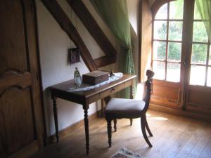 einen Schreibtisch in einem Zimmer mit einem Stuhl und einem Fenster in der Unterkunft la maison d'hôtes de plessis in Plessis-Saint-Jean