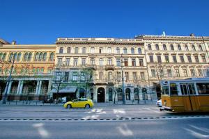 ブダペストにあるHip Apartment at the Museumの大きな建物の前に停車する黄色い車