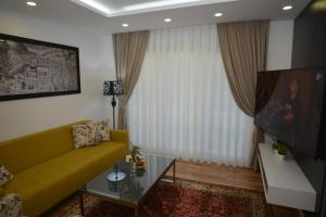 ein Wohnzimmer mit einem gelben Sofa und einem TV in der Unterkunft Apart Hotel Family in Sarajevo
