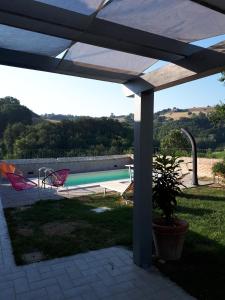 un patio con mesa, sillas y piscina en Nidastore Holidays, en Arcevia