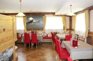 un restaurant avec des chaises et des tables rouges dans une salle dans l'établissement Hotel Stella Montis, à Campitello di Fassa