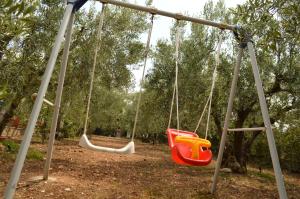 two swings in a park with trees in the background at Ground beach studio in Nea Potidaea