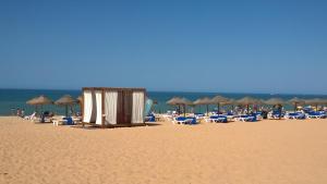 a beach with lounge chairs and umbrellas and the ocean at Sea view - top floor in Quarteira