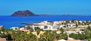 widok na plażę z domami i ocean w obiekcie The Ohana Beach Apartment w Corralejo