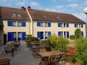 ein Gebäude mit Holztischen und blauen Fenstern in der Unterkunft Comfort Hotel Etampes in Étampes