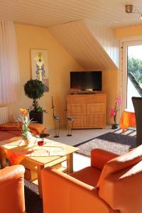 sala de estar con muebles de color naranja y TV de pantalla plana. en Ferienwohnungen Mantke SNF zertifiziert, en Gronau