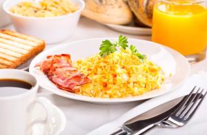 a plate of scrambled eggs and bacon on a table at Hotel Apartamento Solverde in Espinho