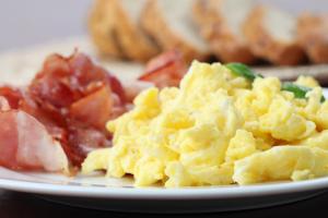 a plate of scrambled eggs and bacon on a table at Hotel Apartamento Solverde in Espinho