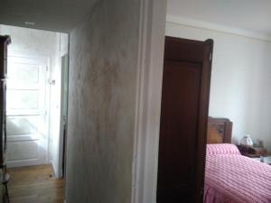 um quarto com uma cama com lençóis cor-de-rosa e uma porta em Chez Mamie em Beynat