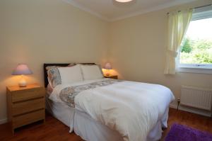 a bedroom with a bed with two lamps and a window at Amber Lodge in Hunters Quay