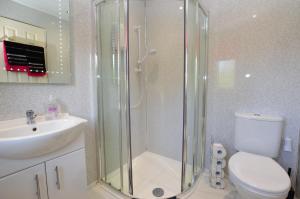 a bathroom with a shower and a toilet and a sink at Amber Lodge in Hunters Quay +13 photos