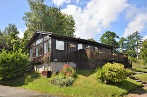 a black house with a balcony on the grass at Amber Lodge in Hunters Quay