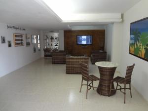 Habitación con mesa, sillas y TV. en Laina´s Place Hotel, en Natal