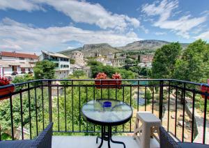 a table on a balcony with a view of a city at Pansion Villa Nur in Mostar