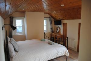Un dormitorio con una cama blanca con techo de madera. en The Castle Bed & Breakfast, en Ballintoy