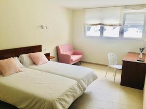 - une chambre avec deux lits et une chaise rose dans l'établissement Vendaval, à Ortigueira