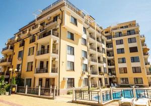 un gran edificio amarillo con una piscina frente a él en Dom-El Real Apartments in Raduga Complex, en Sveti Vlas