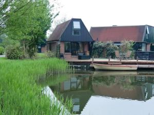 una casa en el agua con un barco delante en Huisje 59, en Nieuwe-Niedorp