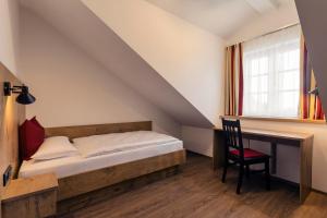 a bedroom with a bed and a desk and a window at Brauerei Gaststätte Stierberg in Obertaufkirchen