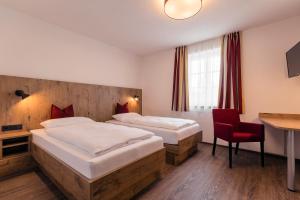 a hotel room with two beds and a red chair at Brauerei Gaststätte Stierberg in Obertaufkirchen