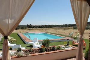 una ventana con vistas a la piscina y sillas en Casa Rural Sierra Jayona, en Fuente del Arco